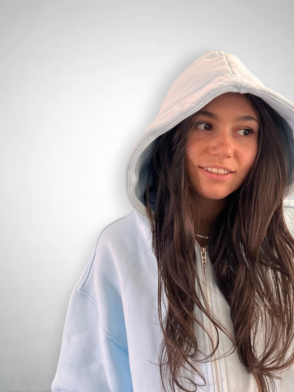 SLAYZ light blue cotton blend zip-up hoodie with a relaxed fit and hood, worn by a young woman.