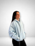 SLAYZ light blue cotton blend zip-up hoodie with pockets and hood on a smiling woman.