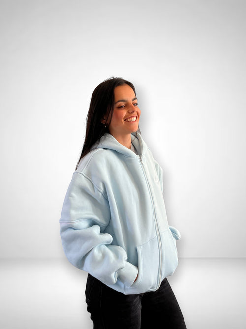 SLAYZ light blue cotton blend zip-up hoodie with pockets and hood on a smiling woman.