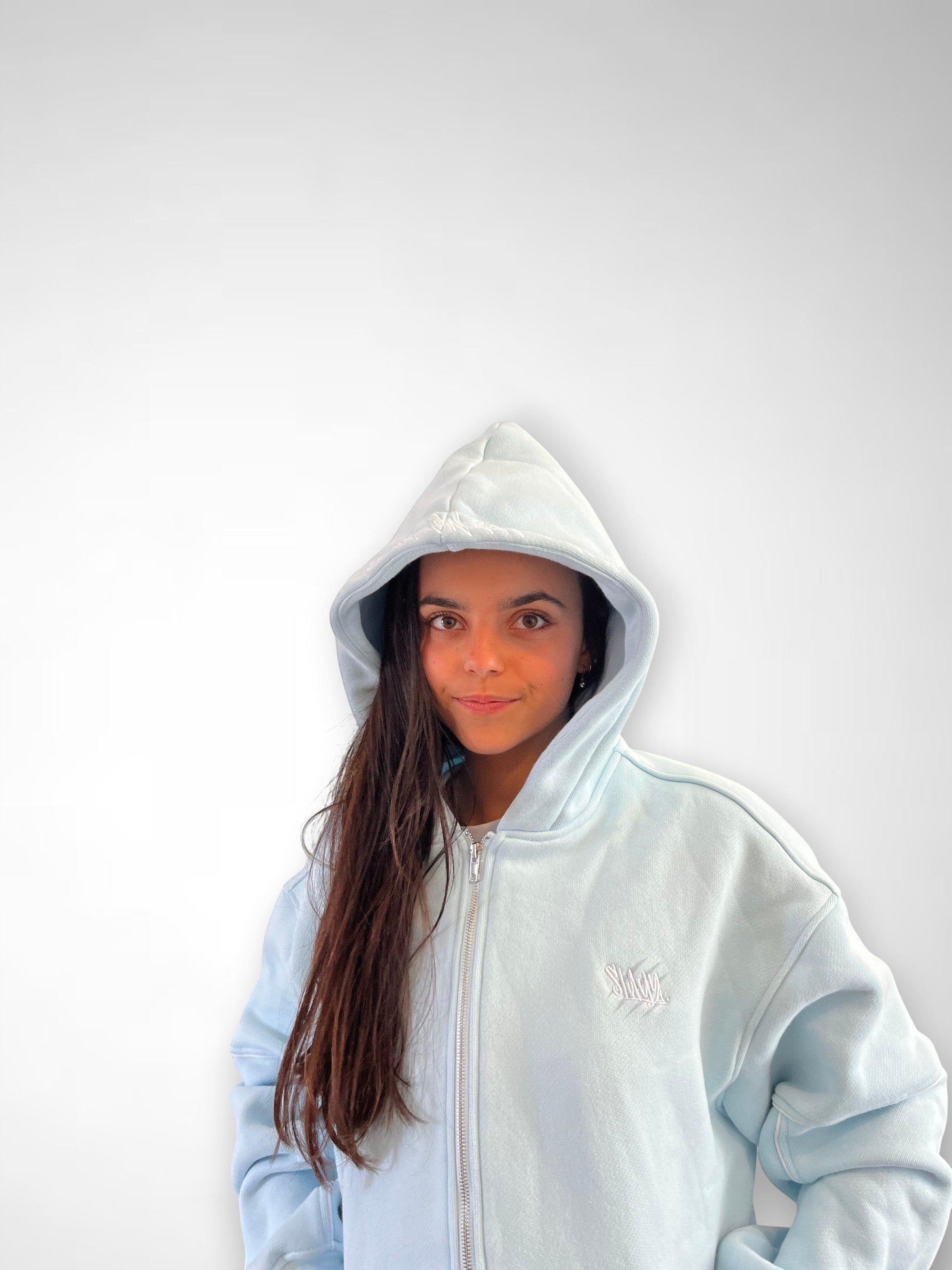 SLAYZ light blue cotton blend zip-up hoodie with a hood and embroidered logo on chest, worn by a young woman.